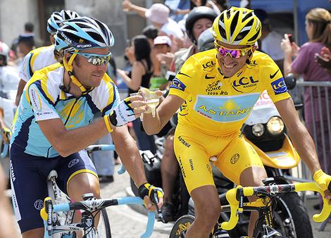 Astana rider Contador and team-mate Paulinho toast with champagne as they ride during the final 21th stage of the 96th Tour de France cycling race